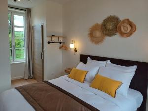 a bedroom with a large bed with yellow and white pillows at La Reinette des Prés in Doudeauville