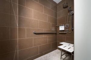 a bathroom with a shower with brown tiles at Hyatt House Naples 5th Avenue in Naples