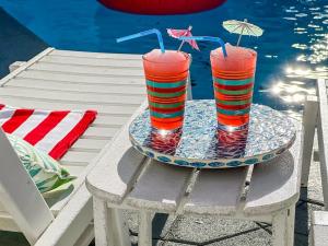 zwei Gläser auf einem Tablett auf einem Tisch neben dem Wasser in der Unterkunft SolMate Free Golf Cart & Pool Heat Deals in Destin