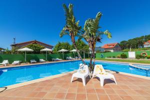 two chairs and a palm tree next to a swimming pool at Hotel Gaivota in Montalvo