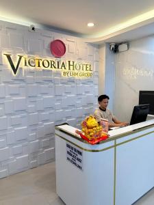 a man sitting at a reception desk with a laptop at Motel Victoria in Ho Chi Minh City