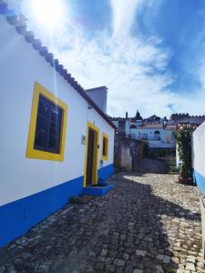 a blue and white house with a yellow door at Casa Nº11 - Vila d'Óbidos in Óbidos