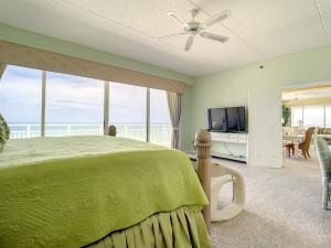 a bedroom with a green bed and a television at Penthouse Condo with wrap around views of the ocean - SR802 in Edgewater