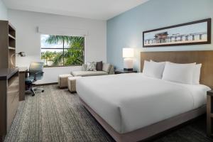 a hotel room with a large white bed and a desk at Hyatt House Naples 5th Avenue in Naples