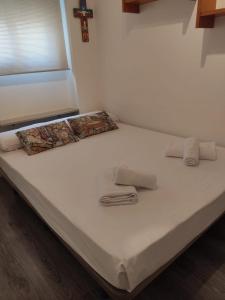un letto con lenzuola bianche e asciugamani pieghevoli di Céntrico Piso de 2 habitaciones a Saragozza