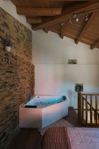 a bath tub in a room with a brick wall at casa Robaleira in Cedeira