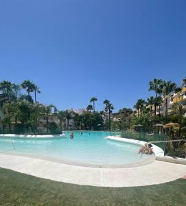 a pool at a resort with people in it at Modern Sea & Golf View 2-Bedroom Apartment with Pool and Terrace in Calanova in Mijas +41 photos