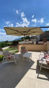 a patio with two chairs and a large umbrella at Serre Alte Landscape Luxury Rooms in Matelica