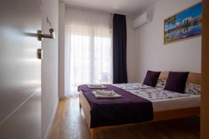 a bedroom with a bed with purple sheets and a window at Apartman Pike centar in Trebinje