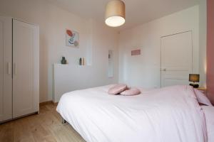 a bedroom with a white bed with pink pillows on it at Appartement Centre-Ville 2/4 personnes in Épernay +7 photos