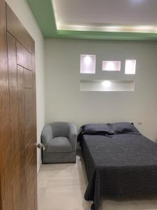 a bedroom with a bed and a chair and a door at AB bed and breakfast in Chihuahua