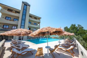 a group of chairs and umbrellas next to a swimming pool at Emara Boutique Hotel in Kavajë