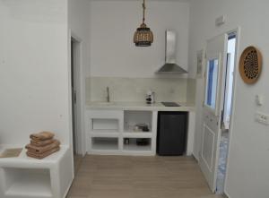 a white kitchen with a sink and a counter at Belvedere Studios in Astypalaia Town