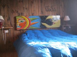 a bedroom with a bed with paintings on the wall at Cabañas Caleta San Pedro in La Serena