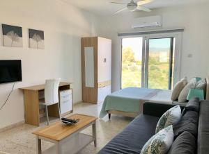 a living room with a couch and a bed and a television at White House studio with sea view and parking in Polis Chrysochous