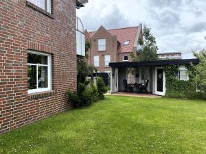 ドルヌマージールにあるFerienwohnung in Dornumersiel für 6 Personenのレンガ造りの家(パティオ、芝生の庭付)
