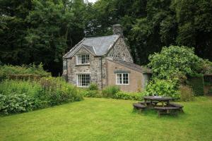 an old stone house with a picnic table in the yard at Garden Cottage in Pwllheli