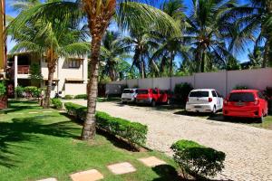 a row of cars parked in a parking lot with palm trees at Pipa Beleza Suítes in Pipa