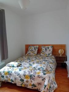 a bedroom with a bed with a floral bedspread and pillows at Maison à Eu proche centre ville et baie de Somme in Eu +1 photo