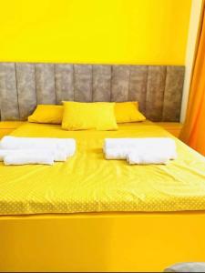 Un dormitorio amarillo con una cama con toallas. en Gonio Family inn, en Gonio