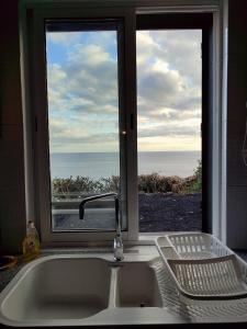 a kitchen sink and a window with a view of the ocean at Casa do Moinho in Lajes do Pico