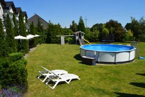 a backyard with a pool and two chairs and a table at Dom Aurora - Pokoje 2, 3, 4 osobowe nad morzem in Dziwnówek