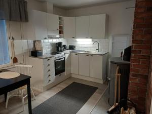 a kitchen with white cabinets and a brick wall at Loma Kallioniemi in Ähtäri +14 photos