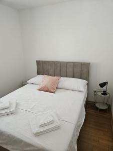 a large bed with white sheets and a pink pillow at Klara in Vodice