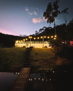 un edificio con luces al lado de un cuerpo de agua en Hosperdagem no Ônibus Off White em Santa Teresa no Circuito Caravaggio, en Santa Teresa