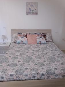 ein Schlafzimmer mit einem Bett mit einer grau-rosa Tagesdecke in der Unterkunft Casa Ester in Ascea