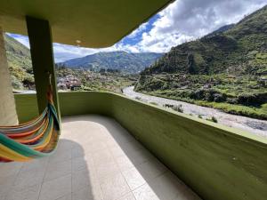 a balcony with a hammock and a view of a river at La Casa Verde Eco Guest House in Baños +28 photos