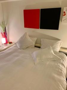 ein weißes Bett mit weißen Kissen und einem roten Gemälde an der Wand in der Unterkunft Superbe appartement digue vue mer in Knokke-Heist + 13 Fotos