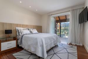 a white bedroom with a bed and a television at Casa Bellavista, 4 suítes A/C, Sauna, Vista in Petrópolis +40 photos