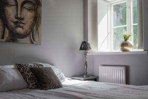 a bedroom with a bed with a painting of a woman at Charming Garden View Apartment with Terrace & grill in Visby +5 photos