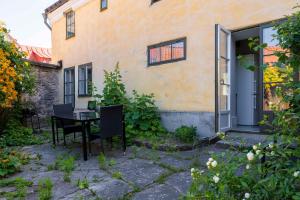 a patio with a table and chairs in front of a building at Charming Garden View Apartment with Terrace & grill in Visby