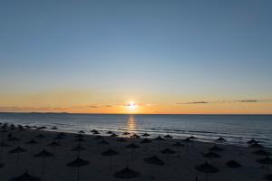 a group of umbrellas on the beach at sunset at Perla Penthouse - Happy Rentals in Mullini i Danit