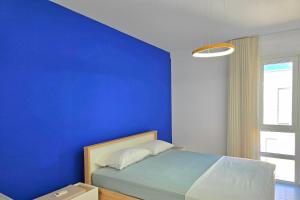 a blue bedroom with a bed with a blue wall at Swiss Sweet Apartment 297 - Happy Rentals in Lalzit Bay