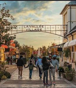 a group of people walking down a street under a bridge at Appartement paris Disneyland in Bussy-Saint-Georges