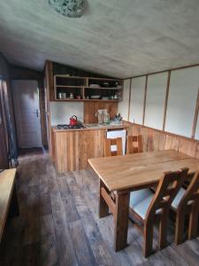 a dining room with a wooden table and a kitchen at Apartament HOLENDER na Polu namiotowym RADOŚĆ in Okuninka