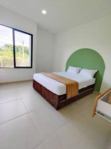 a bedroom with a bed with a green headboard and a window at Casa Arbórea - Casa Campestre con piscina in Acacías
