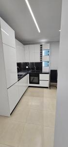 una cocina blanca con armarios blancos y una silla en GPN Sole apartment, en Vlorë