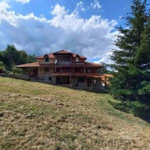 a large house sitting on top of a grass field at Studio Eva Vlasinsko Jezero in Vlasina Okruglica