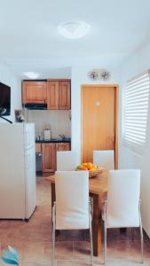 a kitchen with a wooden table and white chairs at Two rooms Hvar spa & apartments in Vrboska