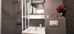 een badkamer met een wastafel, een spiegel en bloemen bij Brand New Place in Rovinj