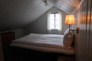 Un dormitorio con una cama con una lámpara y una ventana. en Lillehuset, en Kabelvåg