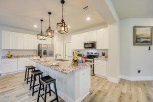 a kitchen with white cabinets and a large island with bar stools at San Antonio Home with Fenced-In Yard Steps to Park! in San Antonio