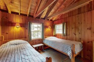 two beds in a room with wooden walls at White Birches in Northport