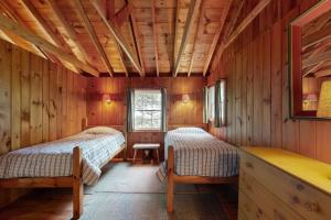 two beds in a room with wooden walls at White Birches in Northport