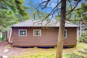 a log cabin in the woods with a tree at White Birches in Northport