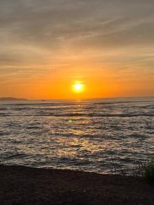 una puesta de sol sobre el océano con la puesta de sol en Casa Pé Na Areia - Praia Grande ES, en Fundão